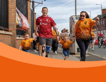 Family of mum and dad with two little boys run towards camera wearing orange shirts