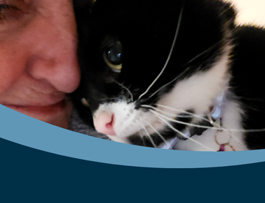 Close up image of a black and white cat nuzzling its head against a white woman's face