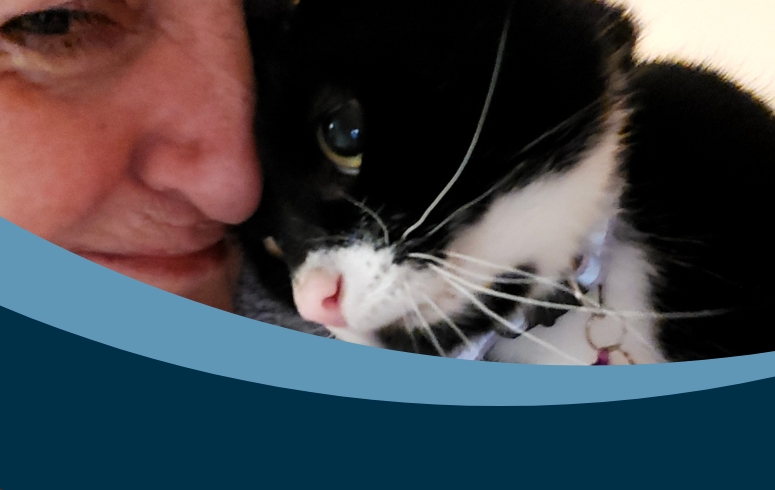 Close up image of a black and white cat nuzzling its head against a white woman's face