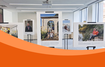 The image displays several large framed photographs on stands in an indoor setting, part of the exhibition.