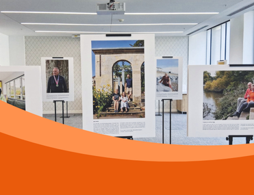 The image displays several large framed photographs on stands in an indoor setting, part of the exhibition.