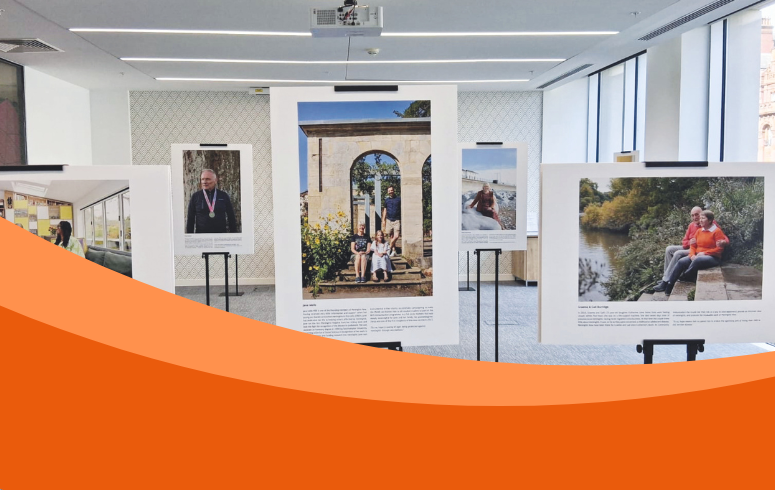 The image displays several large framed photographs on stands in an indoor setting, part of the exhibition.