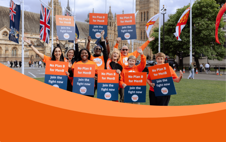 A group of individuals holding "No Plan B for MenB" signs stand together in front of the UK Parliament building. Flags are visible in the background.
