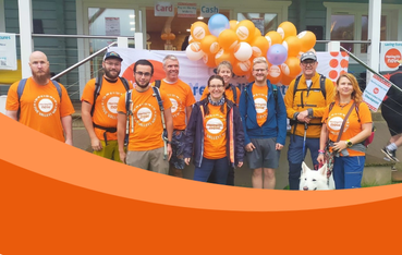 A mixed age group of walkers wearing Meningitis Now t-shirts standing in front of orange balloons