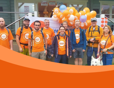 A mixed age group of walkers wearing Meningitis Now t-shirts standing in front of orange balloons