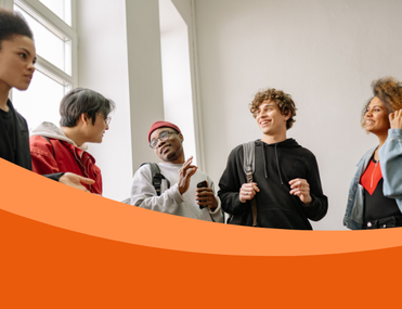 A group of 5 young people of different ethnicities talking and smiling in a corridor