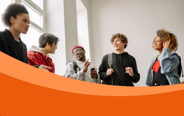 A group of 5 young people of different ethnicities talking and smiling in a corridor