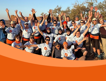 Large group of people, many wearing sunglasses and t-shirts look at the camera, some with arms above their heads