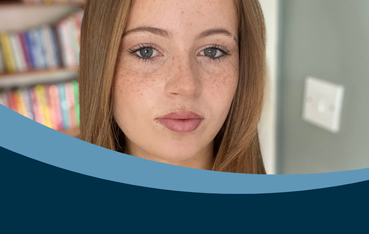 White woman with auburn hair and freckles looks directly into the camera