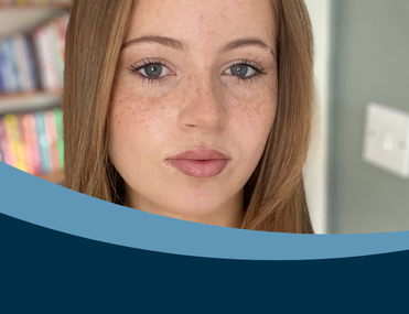 White woman with auburn hair and freckles looks directly into the camera