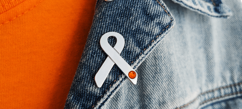 A silver ribbon badge pinned on someone wearing a denim jacket