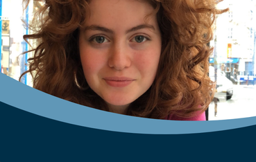Young woman with curly auburn hair looking at camera