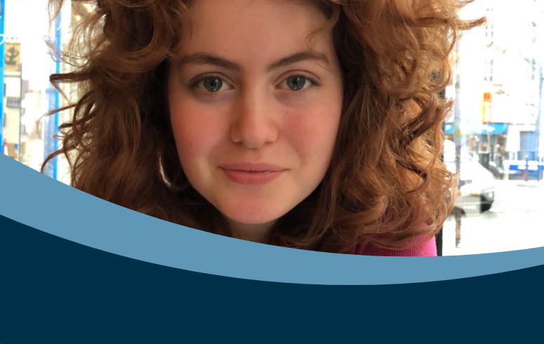 Young woman with curly auburn hair looking at camera