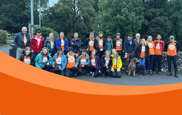Large group of people wearing orange t-shirts and coats pose for photo