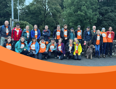 Large group of people wearing orange t-shirts and coats pose for photo