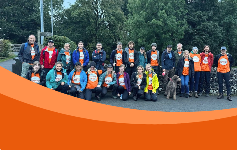 Large group of people wearing orange t-shirts and coats pose for photo