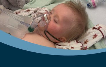 Baby in hospital bed with breathing apparatus