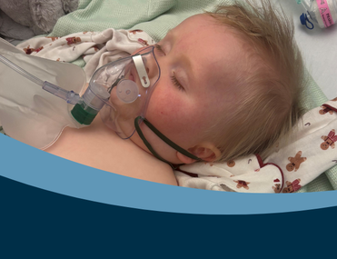 Baby in hospital bed with breathing apparatus